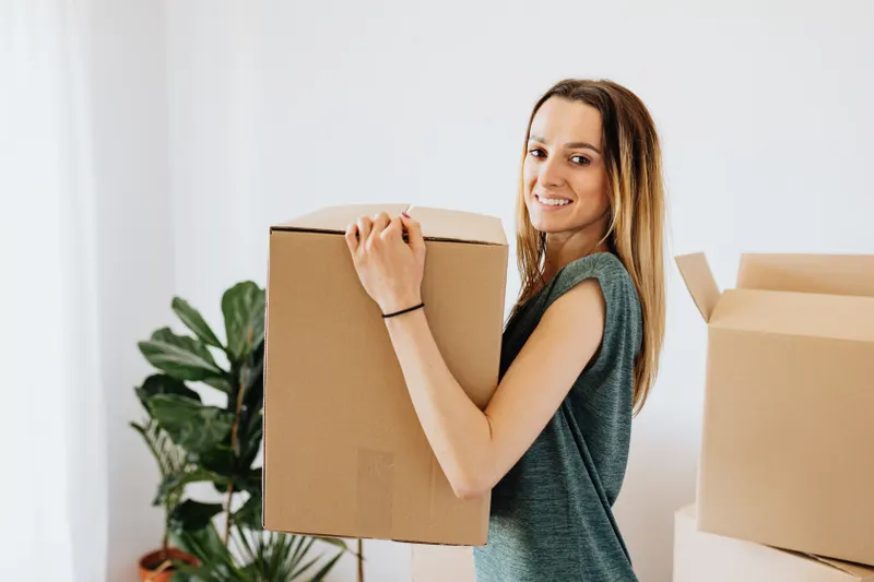 Tânără zâmbitoare care ține o cutie de mutare